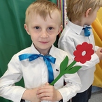 chłopiec w białej koszuli z niebieską wstążką trzyma drewniany kwiatek.jpg