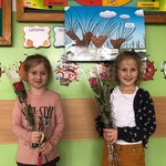 dwie dziewczynki uśmiechnięte trzymają kwiatki.jpg