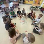 Grupa dzieci siedzi na podłodze w kole, układają karty w zabawie MOSTY..jpg