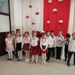 Grupa dzieci z Zerówki na tle czerwono-białego materiału recytuje wiersze.jpg